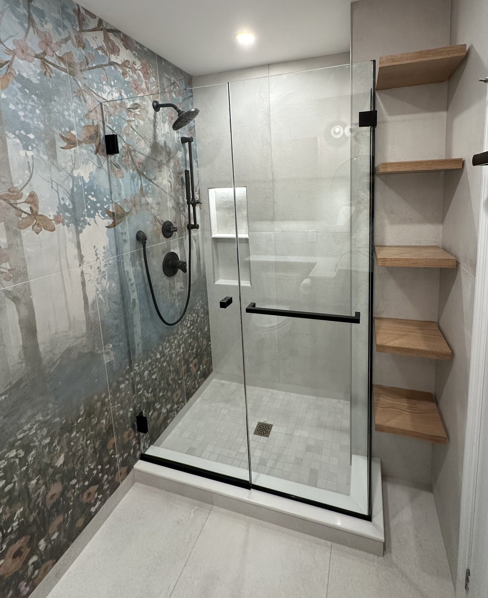 A walk-in shower with a large-scale landscape mural panel, pebble floor and open timber shelving