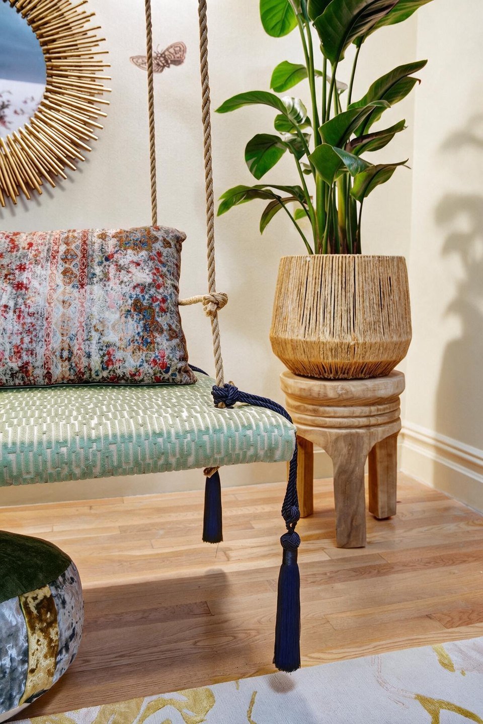 A rope swing bench with a sunburst mirror and a potted palm