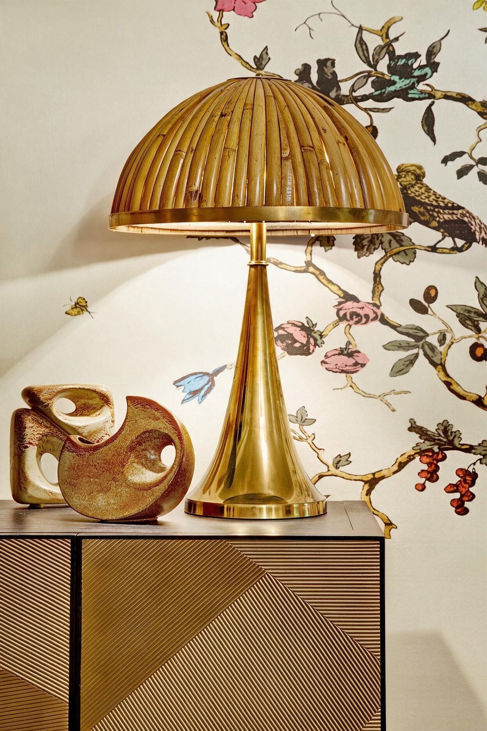 A brass dome lamp and sculptural ceramics on a geometric cabinet