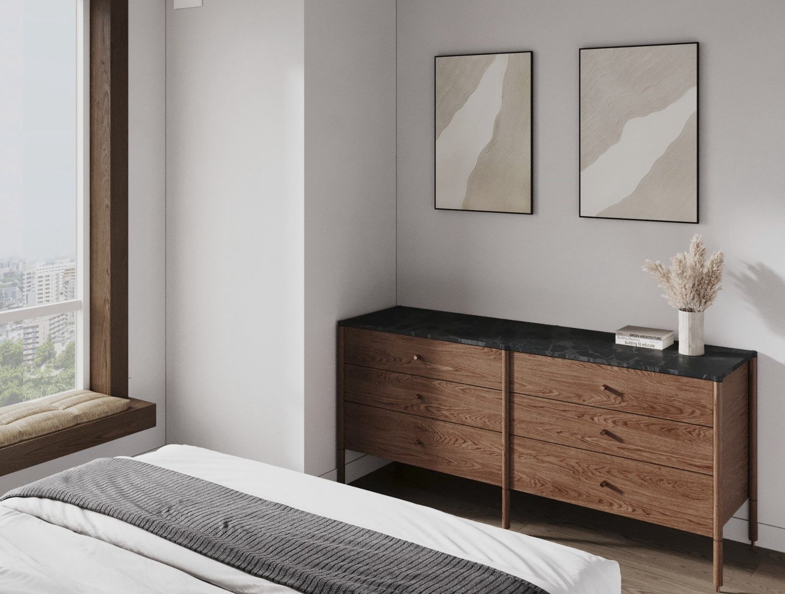 A walnut dresser with a black stone top and paired abstract prints beside a bed