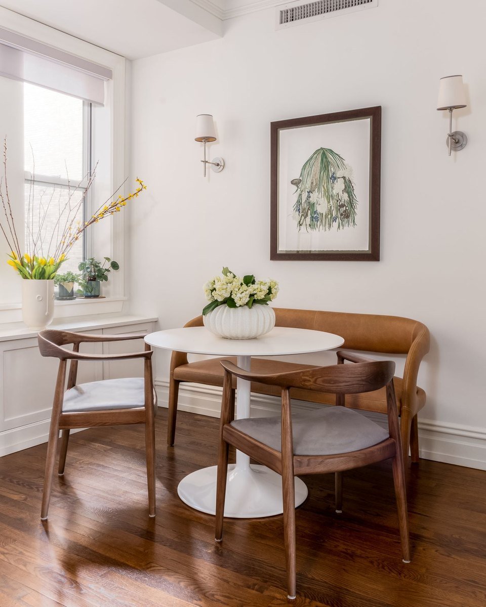 A breakfast nook with a round table under a framed botanical print
