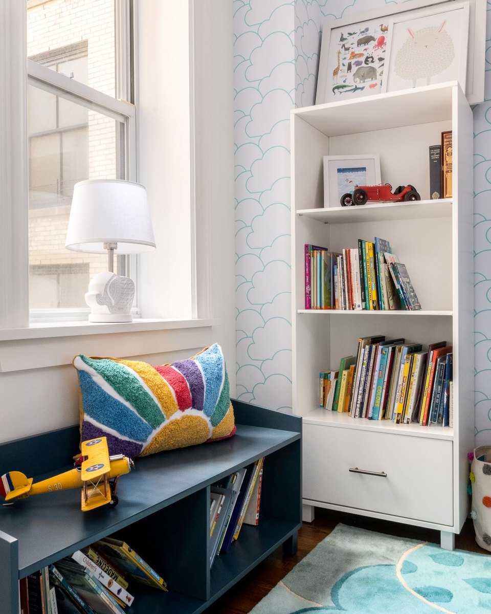 A window bench with book storage beside a white bookcase