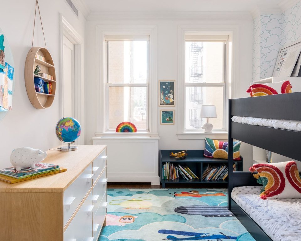 A children's room with twin windows and a soft blue rug