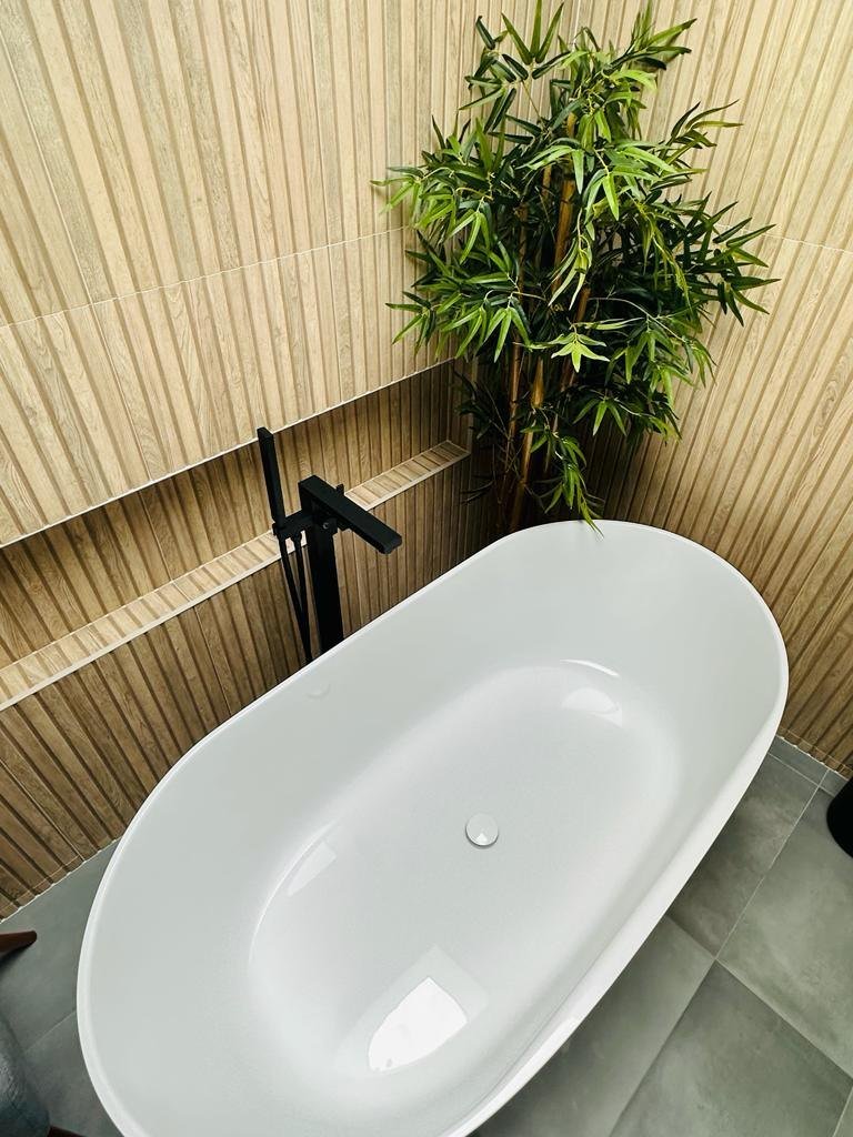 A freestanding tub against a slatted oak wall with bamboo