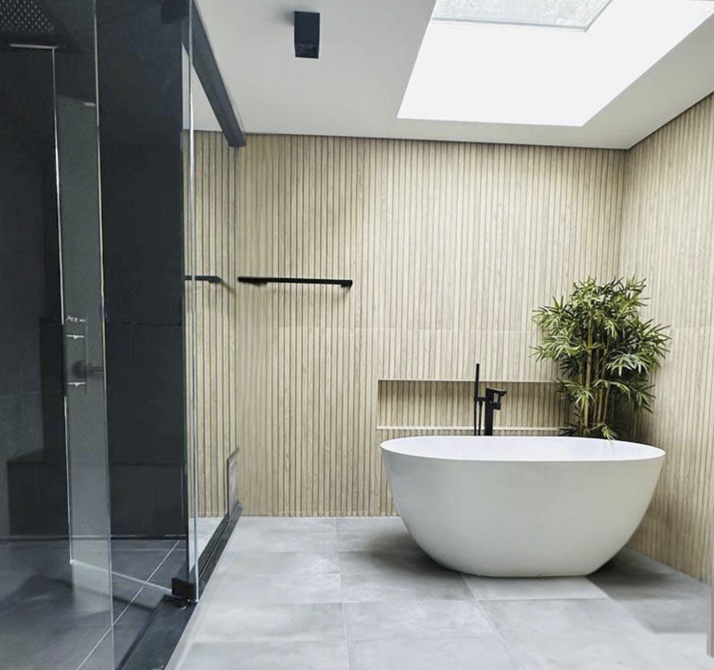 A freestanding tub under a skylight beside a black glass steam shower