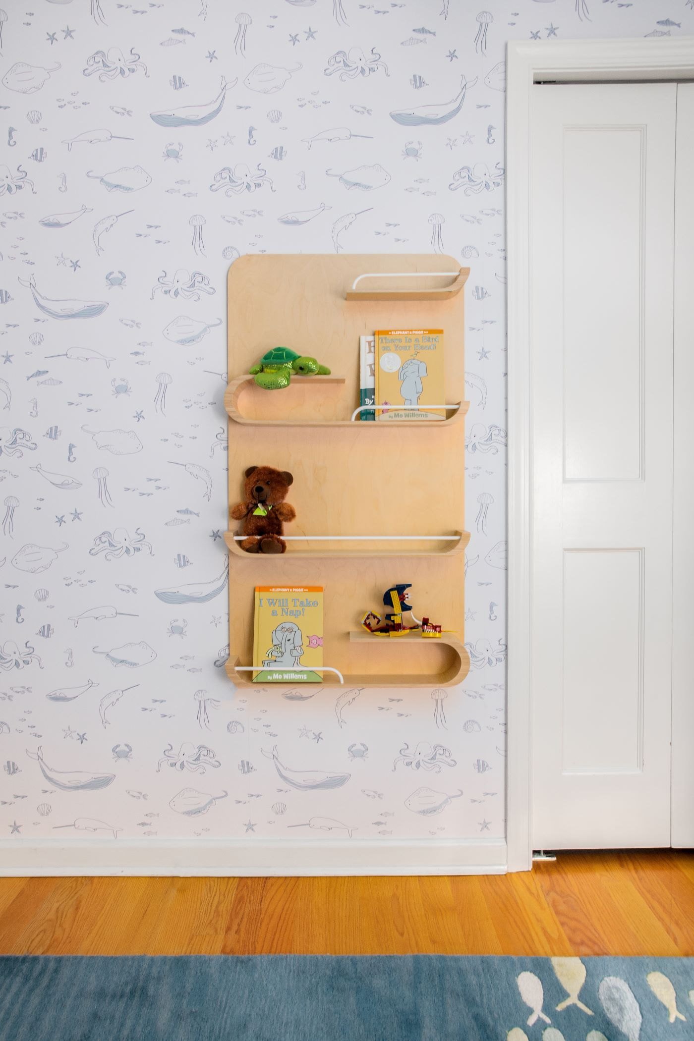 Curved plywood wall shelves holding toys and books beside a panelled door