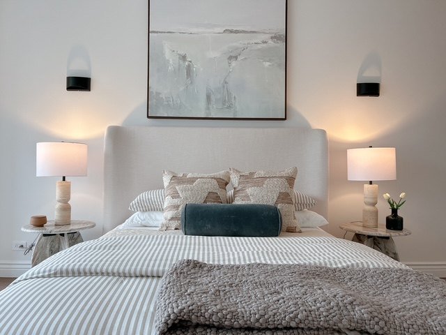 A soft, pared-back bedroom with paired lamps and abstract art
