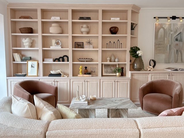 A living room with built-in shelving, leather armchairs and a marble coffee table