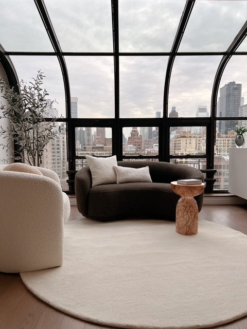 Curved lounge chairs beneath an arched conservatory window
